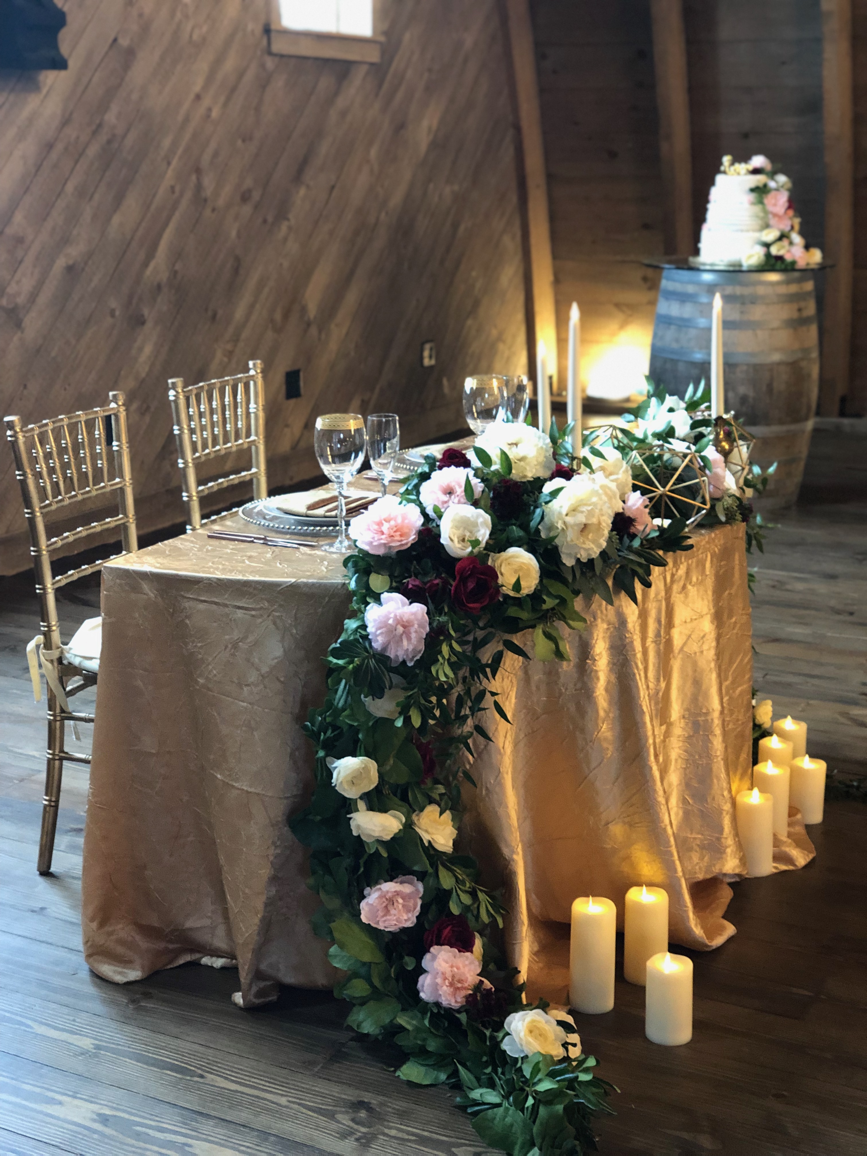 Sweetheart table with gold satin linen and floral arrangement