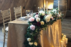 Sweetheart table with gold satin linen and floral arrangement