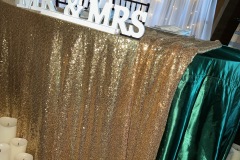 Sweetheart table with gold sequin and emerald satin linen